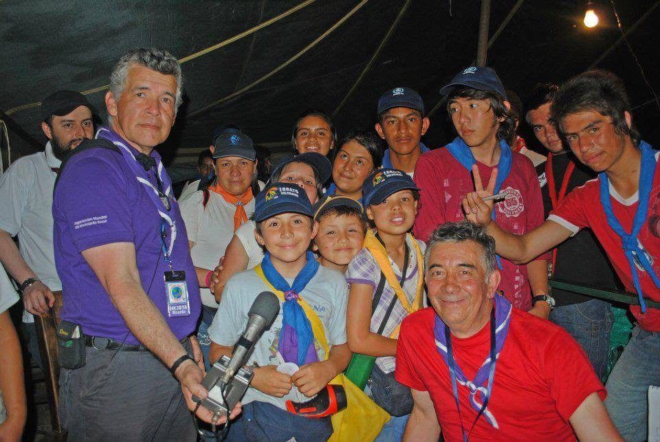 Un grupo grande de scouts, lobatos y dirigentes posa sonriente con un micrófono