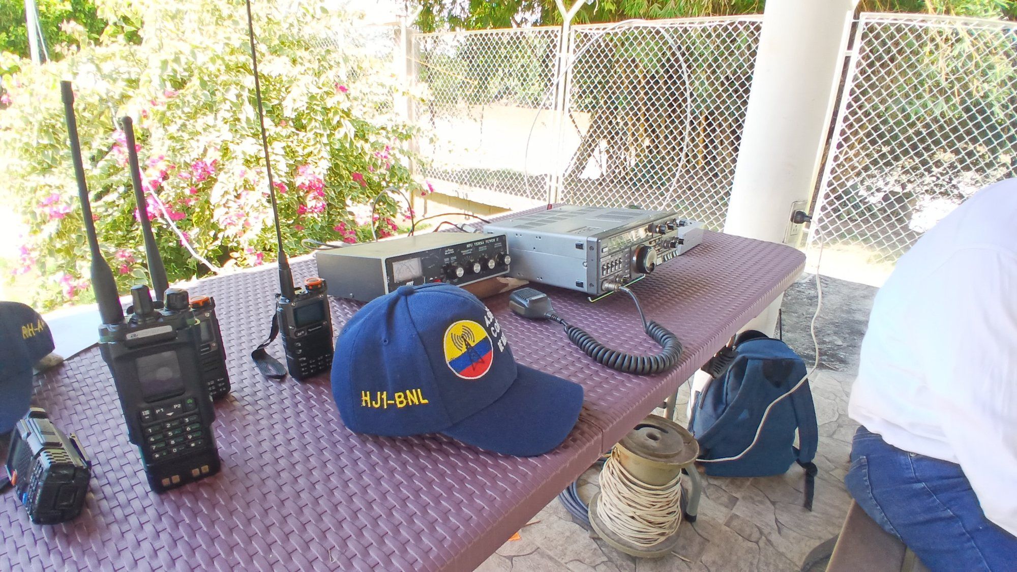 Radios portátiles, un transceptor y una gorra con indicativo sobre una mesa