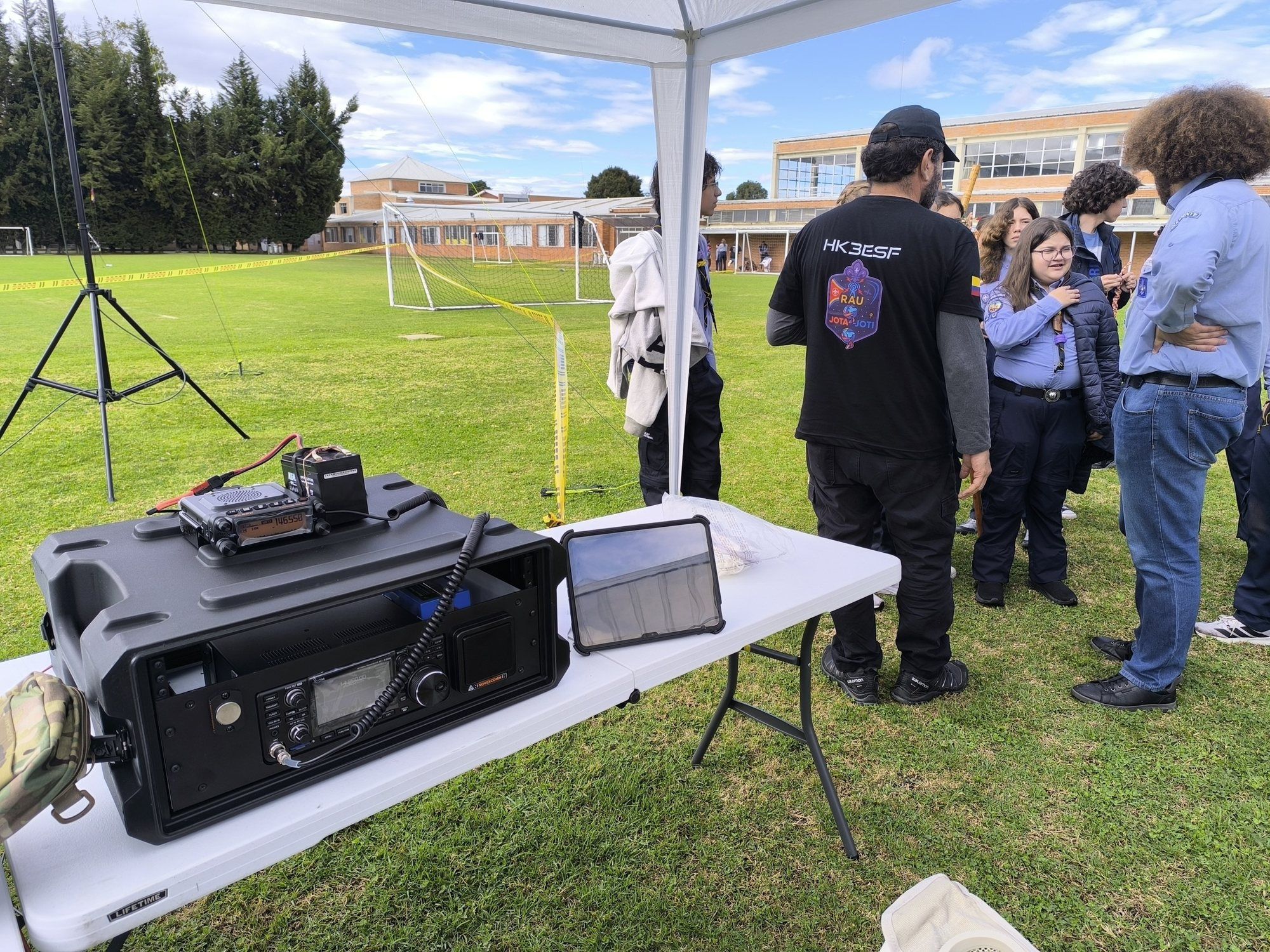 Estación de radio portátil en un maletín, con scouts y un operador al fondo