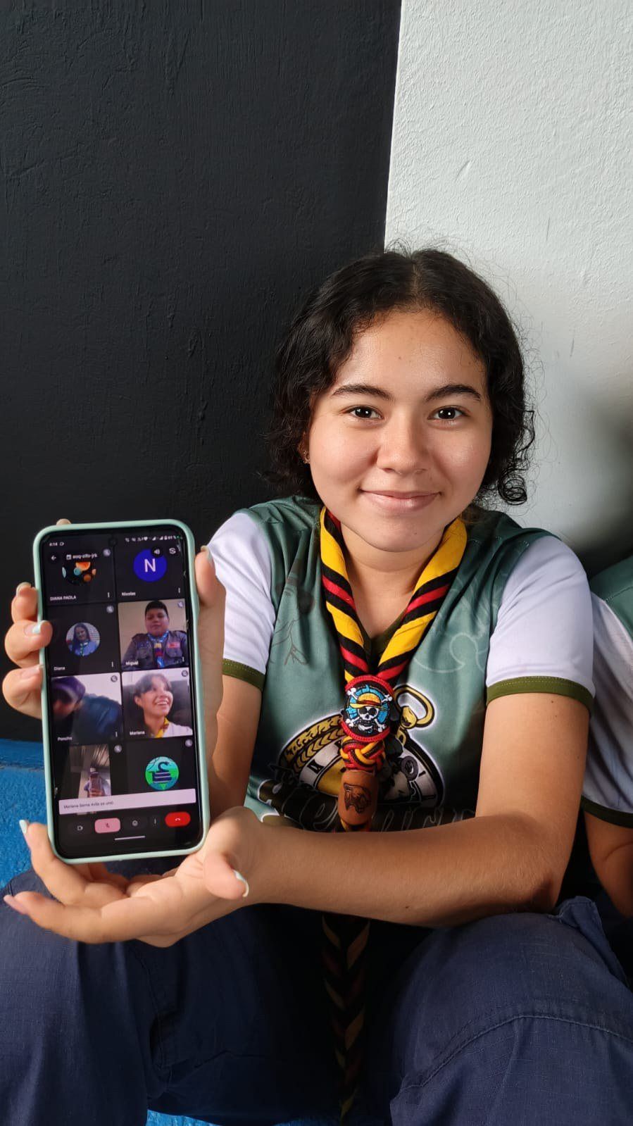 Una scout muestra en su celular una videollamada del JOTI