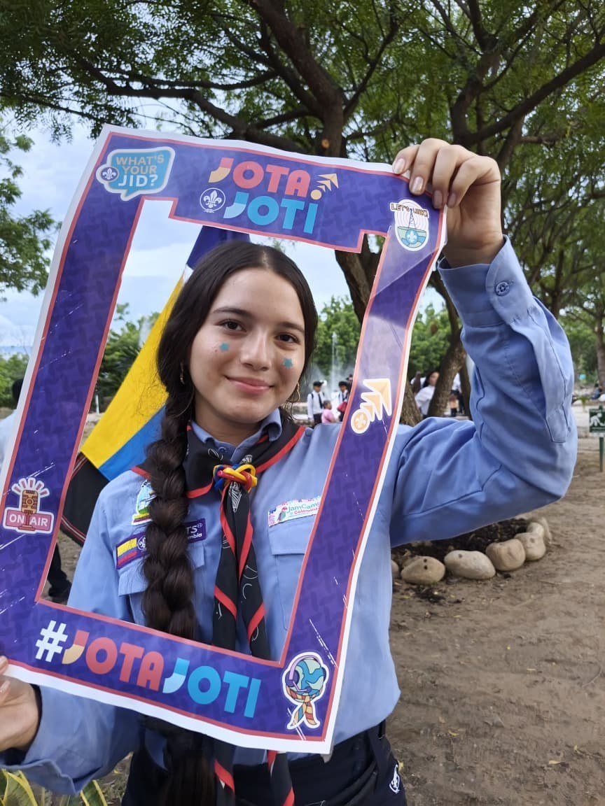 Una scout con la cara pintada posa dentro del marco JOTA-JOTI